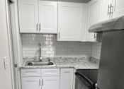 Thumbnail 2 of 21 - a small kitchen with white cabinets and stainless steel appliances