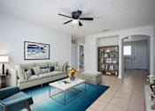 Thumbnail 3 of 12 - a living room with a couch and a coffee table and a ceiling fan