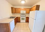 Thumbnail 3 of 30 - A kitchen with white appliances and wooden cabinets.