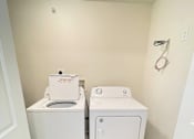 Thumbnail 8 of 30 - A small bathroom with a toilet and a washer and dryer.