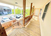 Thumbnail 18 of 30 - A balcony with a railing and a view of a parking lot and trees.