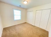 Thumbnail 12 of 30 - A room with a carpeted floor, a window, and a ceiling light.