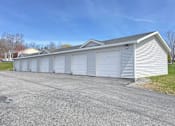 Thumbnail 21 of 30 - A long white garage with a grey roof and a grey driveway.