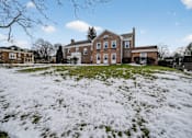 Thumbnail 6 of 17 - A large brick house with a white door and windows.