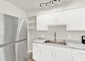 Thumbnail 22 of 31 - A modern kitchen with a stainless steel refrigerator and white cabinets.