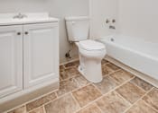 Thumbnail 16 of 38 - A white toilet sits in a bathroom next to a sink and a bathtub.