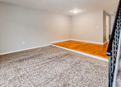 Thumbnail 8 of 17 - A room with a wooden floor and a carpeted area.
