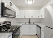 Thumbnail 5 of 26 - A kitchen with white cabinets and a marble countertop.