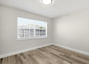 Thumbnail 9 of 26 - A room with a window and wooden flooring.