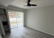 Thumbnail 13 of 23 - A room with a ceiling fan and sliding glass doors.