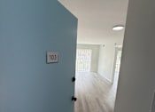 Thumbnail 18 of 23 - A hallway with a door on the left and a light on the ceiling.