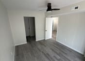 Thumbnail 14 of 23 - A room with a ceiling fan and a doorway leading to another room.