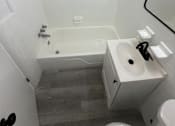 Thumbnail 16 of 23 - A white bathroom with a tub, sink and toilet.