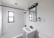 Thumbnail 7 of 49 - A white bathroom with a white tub and sink.