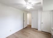 Thumbnail 33 of 49 - A room with a ceiling fan and wooden floors.
