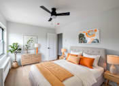 Thumbnail 34 of 49 - A bedroom with a large bed, a ceiling fan, and a painting on the wall.