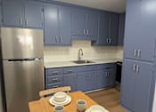 Thumbnail 1 of 28 - A kitchen with blue cabinets and a stainless steel refrigerator.