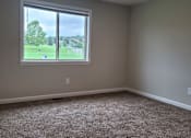 Thumbnail 6 of 26 - A room with a carpeted floor and a window overlooking a green field.