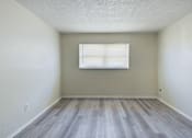 Thumbnail 6 of 18 - A room with a window and wooden flooring.