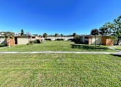 Thumbnail 14 of 18 - A grassy field with apartment buildings in the background.