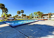 Thumbnail 12 of 18 - A pool surrounded by palm trees and a building in the background.