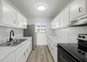 Thumbnail 26 of 41 - A kitchen with white cabinets and a black stove top oven.