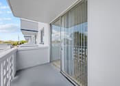 Thumbnail 18 of 41 - A balcony with a glass door and a white railing.