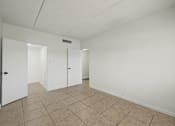 Thumbnail 12 of 25 - A room with white walls and a tiled floor with three white doors.