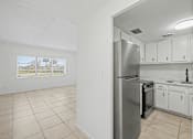 Thumbnail 9 of 25 - A kitchen with white cabinets and a stainless steel refrigerator.