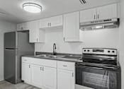 Thumbnail 7 of 26 - A black and white photo of a kitchen with white cabinets and a black stove.