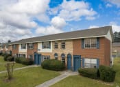 Thumbnail 16 of 17 - a brick apartment building with blue doors and a grass yard
