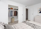 Thumbnail 9 of 17 - a bedroom with a closet and a bed and a closet with clothes hanging on it