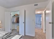 Thumbnail 8 of 17 - a bedroom with white walls and a hallway with a closet and a bed