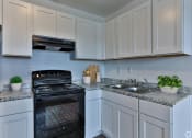Thumbnail 3 of 17 - a kitchen with white cabinets and black appliances and a sink