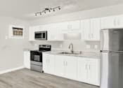Thumbnail 2 of 19 - a white kitchen with stainless steel appliances and white cabinets