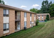 Thumbnail 15 of 19 - a row of brick apartment buildings on a hill with a grass field