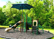 Thumbnail 24 of 26 - A playground with a green umbrella and a slide.