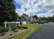 Thumbnail 11 of 15 - A sign for Brookside East Apartments is in front of a house.