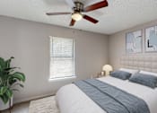 Thumbnail 11 of 17 - A bedroom with a bed, a ceiling fan, and a potted plant.