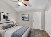 Thumbnail 12 of 17 - A bedroom with a bed, a ceiling fan, and two paintings on the wall.