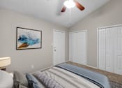 Thumbnail 13 of 17 - A bedroom with a bed, a ceiling fan, and a painting on the wall.