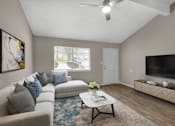 Thumbnail 9 of 17 - A living room with a grey couch, a coffee table, and a television.