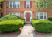 Thumbnail 26 of 31 - A red brick house with a white door and windows.