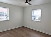 Thumbnail 6 of 15 - A room with a ceiling fan and two windows.