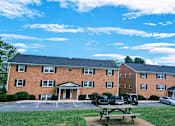 Thumbnail 15 of 15 - A red brick building with a parking lot in front.