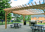 Thumbnail 13 of 15 - A wooden pergola with picnic tables underneath it.