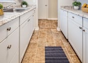 Thumbnail 1 of 17 - A kitchen with white cabinets and a tiled floor.