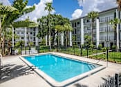 Thumbnail 10 of 12 - A pool in front of a white building surrounded by trees.