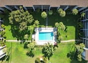 Thumbnail 12 of 12 - A swimming pool surrounded by green grass and trees.