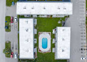 Thumbnail 11 of 14 - A swimming pool is located in the middle of a grassy area surrounded by buildings.